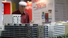 Un hombre contempla la maqueta de varios bloques de pisos / EFE
