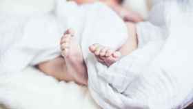 Una niña recién nacida duerme tapada con una manta / CG