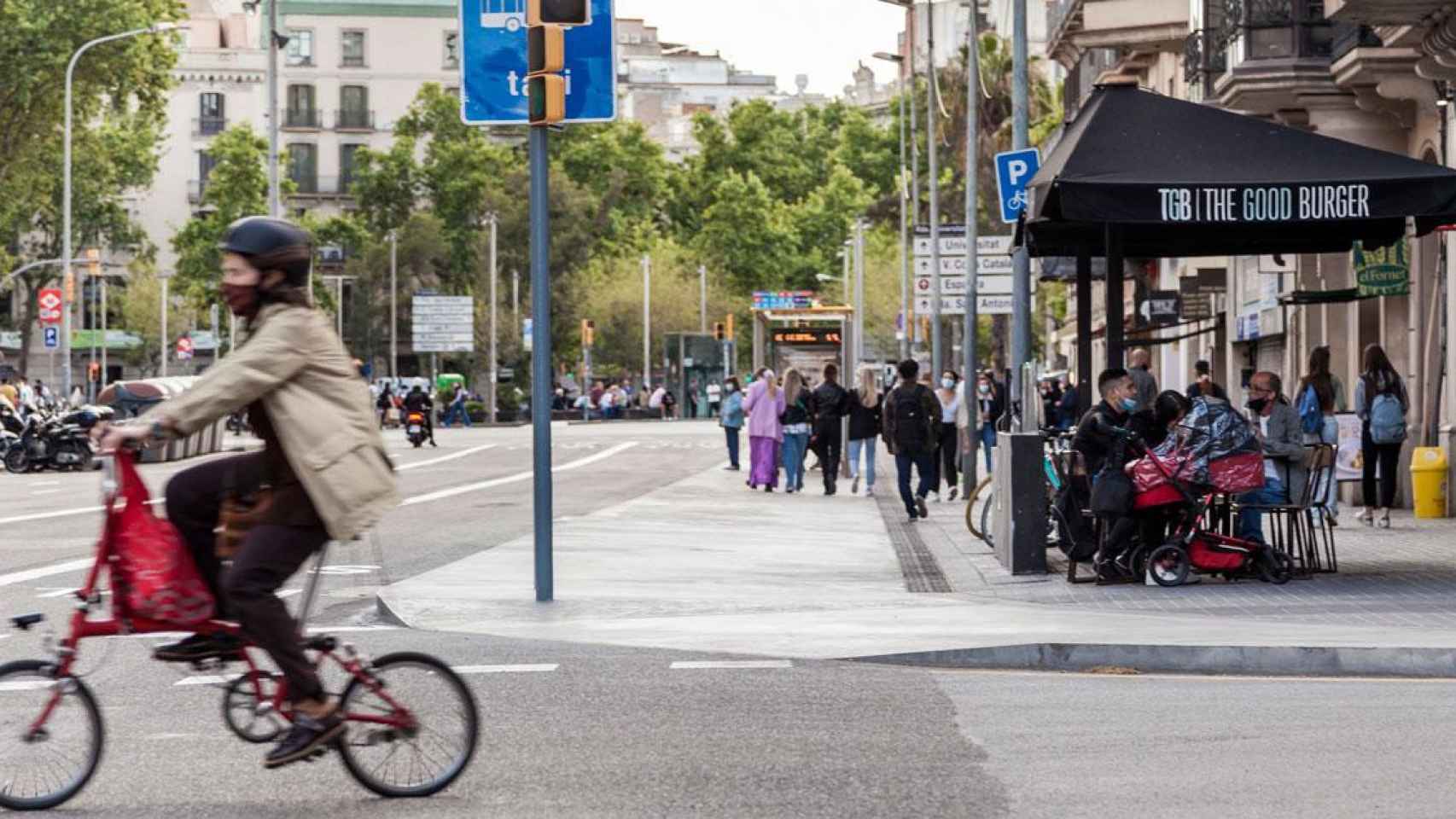 Una bicicleta pasa por delante de una terraza de bar en Barcelona / AJBCN