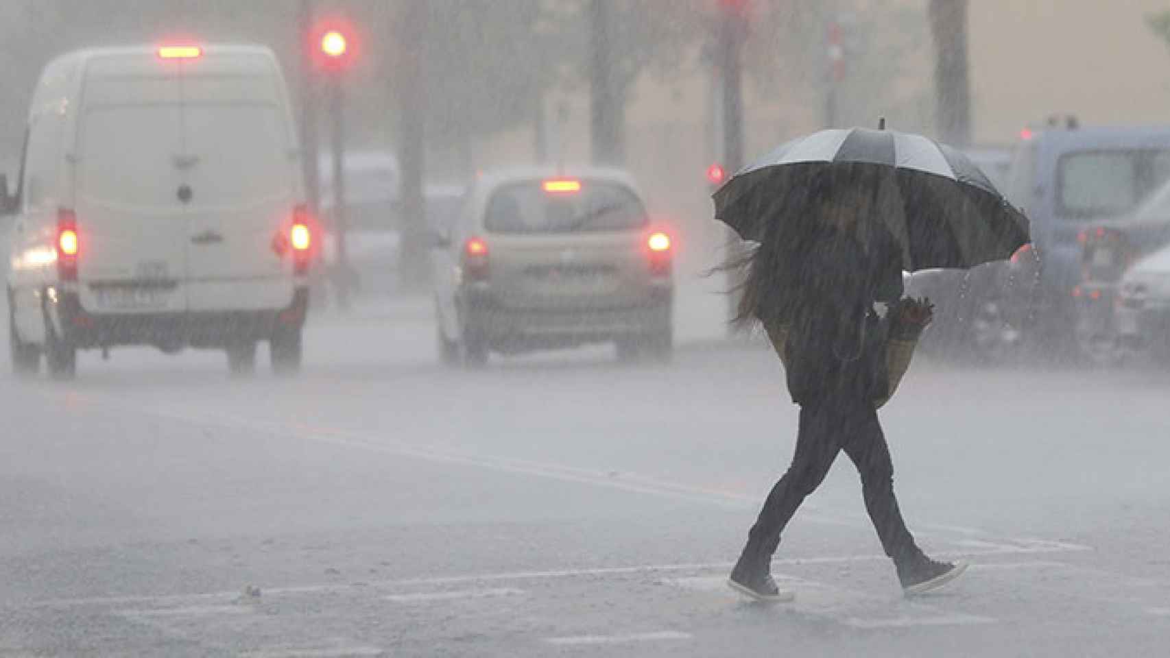 Una persona cruza la calle entre las lluvias, en imagen de archivo / EFE