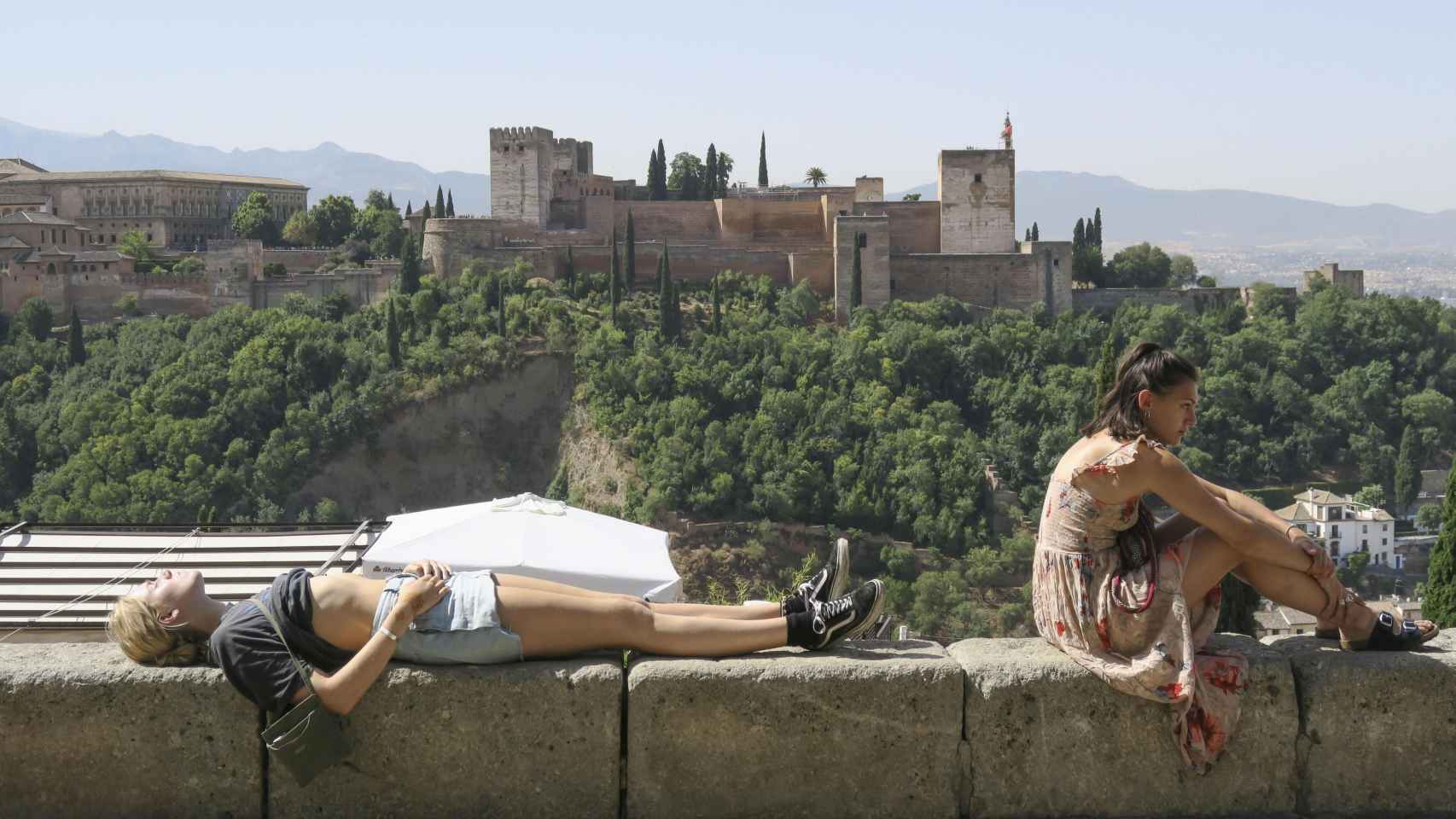 Dos turistas descansan al sol en Granada, una de las provincias en riesgo por la ola de calor / EFE