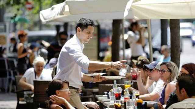 Un camarero atiende a unos turistas en una terraza en Cataluña / EFE
