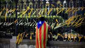Imagen de un independentista colocando lazos amarillos en Barcelona, donde una mujer recibió ayer un puñetazo / EFE