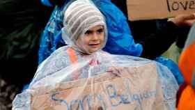 Una niña refugiada sostiene un cartel que dice Lo siento, Bélgica en el campo de Idomeni.