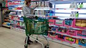 Una mujer compra en un supermercado, con estanterías vacías por el coronavirus / EFE