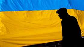 Un hombre camina delante de una bandera de Ucrania / EFE