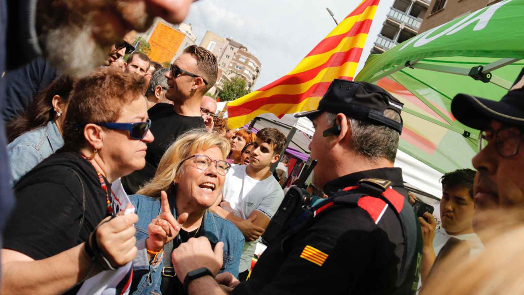 Dos mujeres protestan ante un Mosso d'Esquadra en el escrache a la parada de Sant Jordi de Vox en Sabadell / GALA ESPÍN