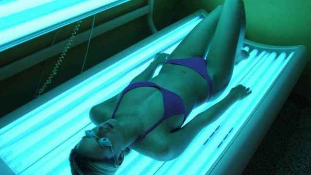 Una mujer dentro de una cabina de bronceado con rayos UVA
