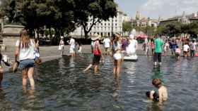 Unos turistas se bañan en la plaza Catalunya de Barcelona durante la ola de calor / CG