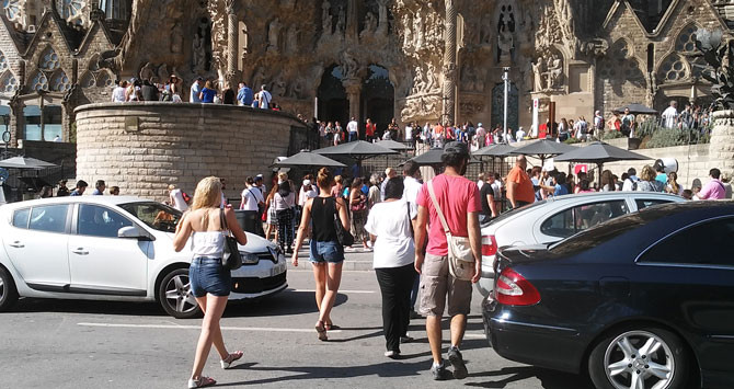 Turistas cruzan pasando entre los coches en la plaza de la Sagrada Familia / CG