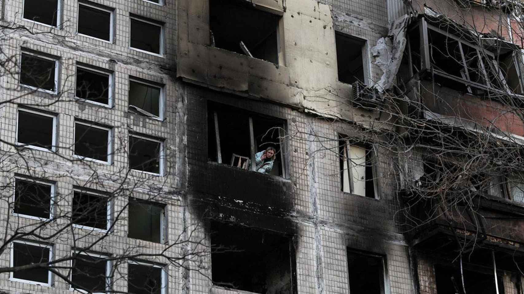 Una mujer se asoma a la ventana de un edificio destruido por un bombardeo ruso en la capital de Ucrania / Miguel A. Lopes (EFE)