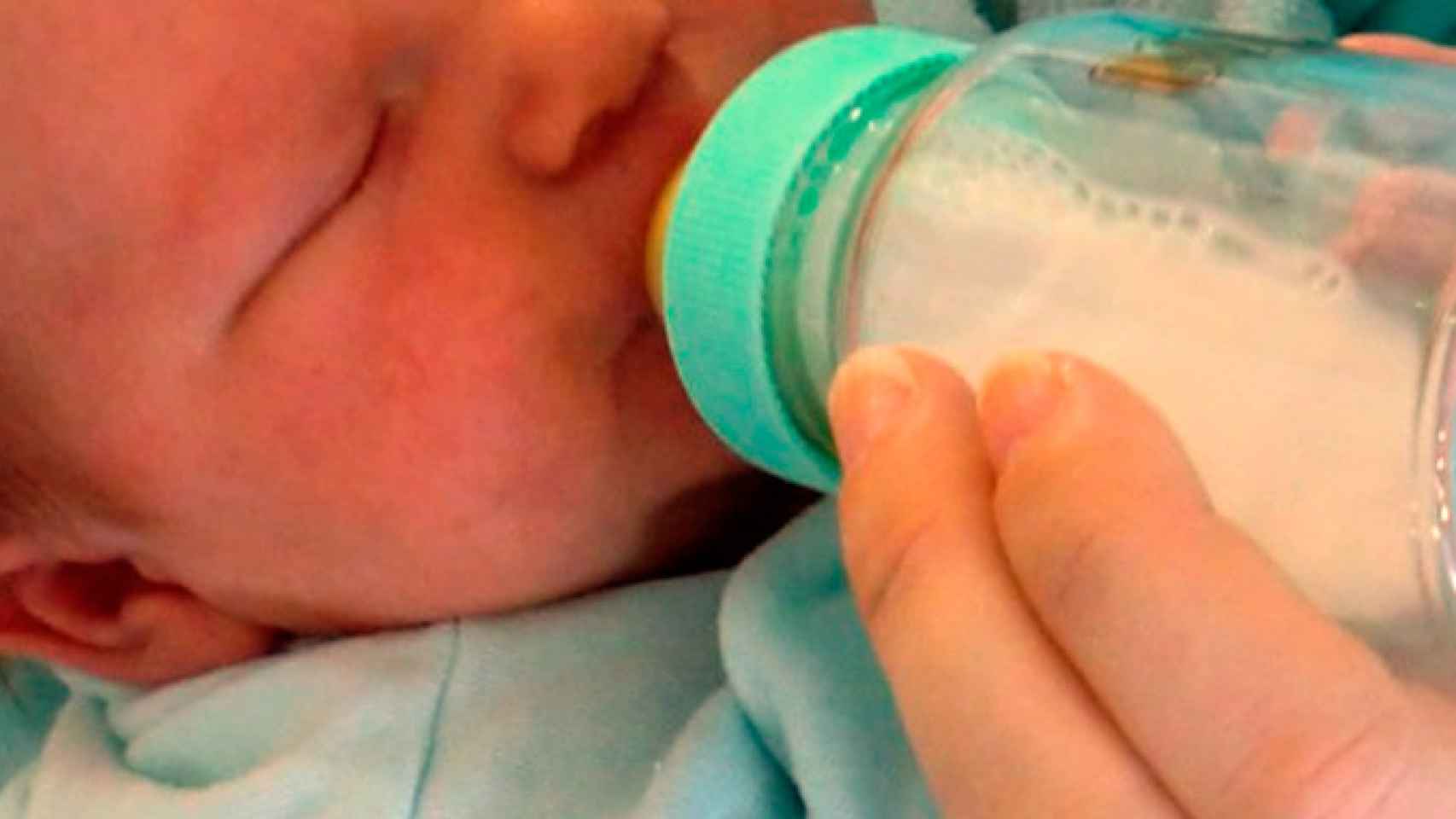 Un bebé bebe leche de un biberón