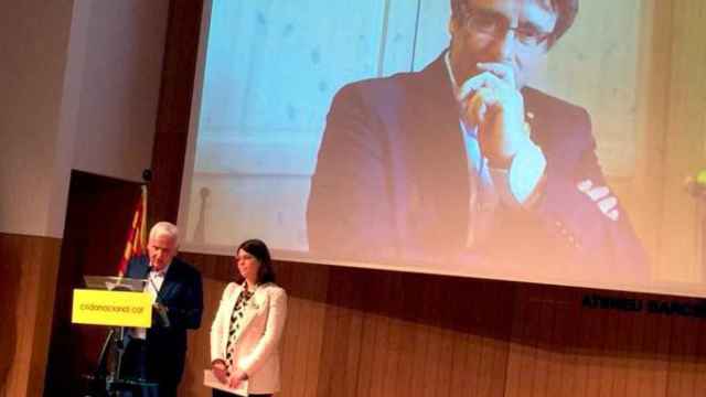 Carles Puigdemont en la pantalla durante la presentación del movimiento Crida Nacional per la República, con Ferran Mascarell en el atril/ CG