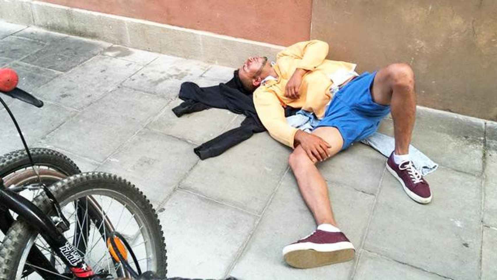 Imagen de un turista echando una cabezadita en plena calle en la Barceloneta / CG