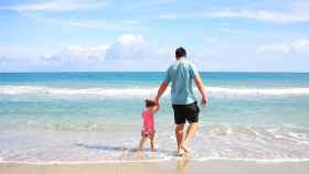 Un padre camina con su hija por la playa. Hay fotoprotectores especiales para cada miembro de la familia / PX