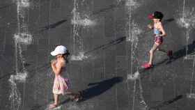 Dos niñas juegan en una fuente en plena ola de calor, que en Cataluña puede alcanzar los 40 grados / EFE