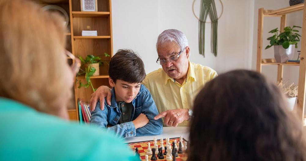Un anciano jugando a montar puzzles con su nieto y su familia / PEXELS