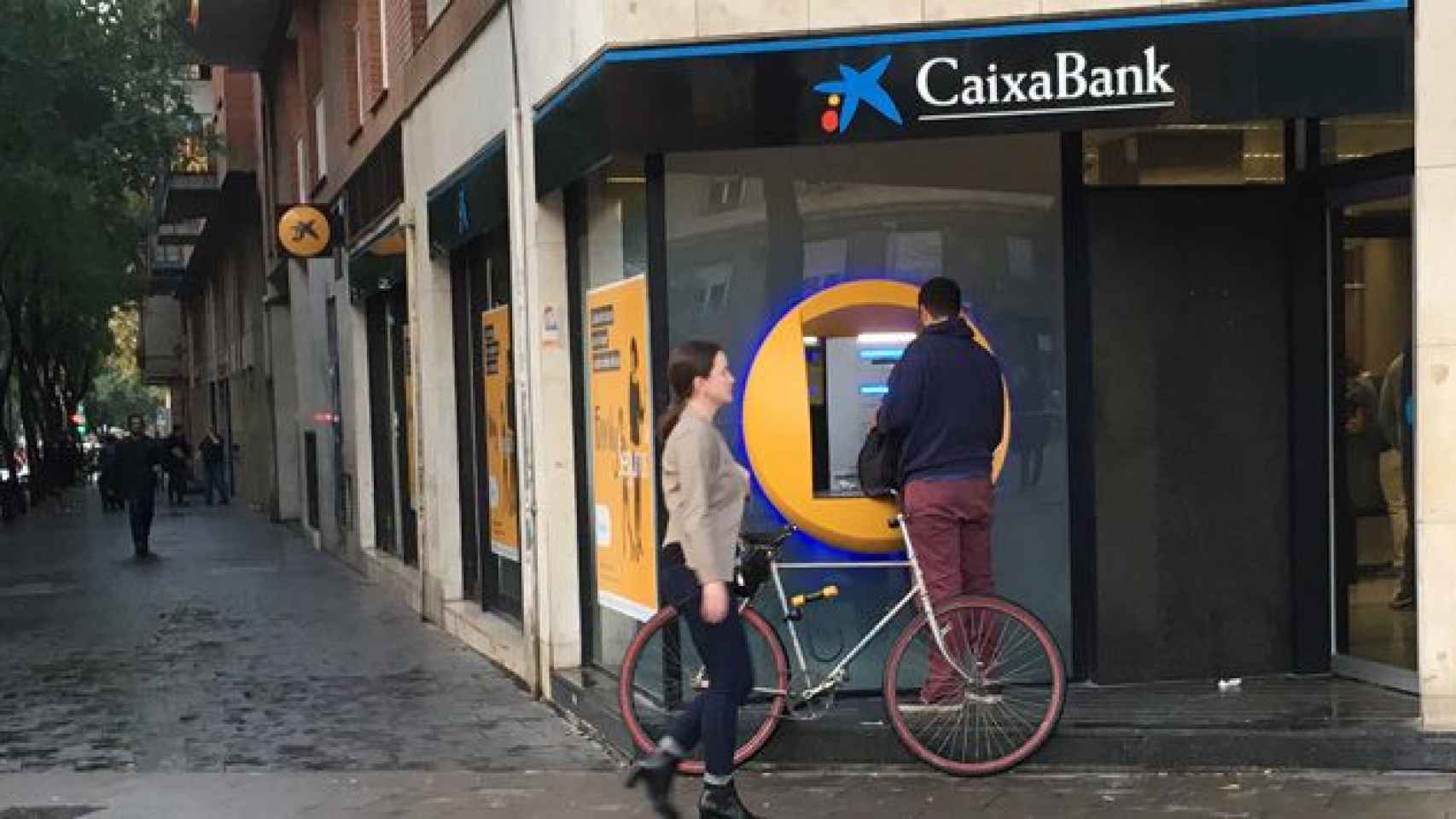 Un hombre retira efectivo en un cajero de Caixabank situado en la calle Marina de Barcelona / CG