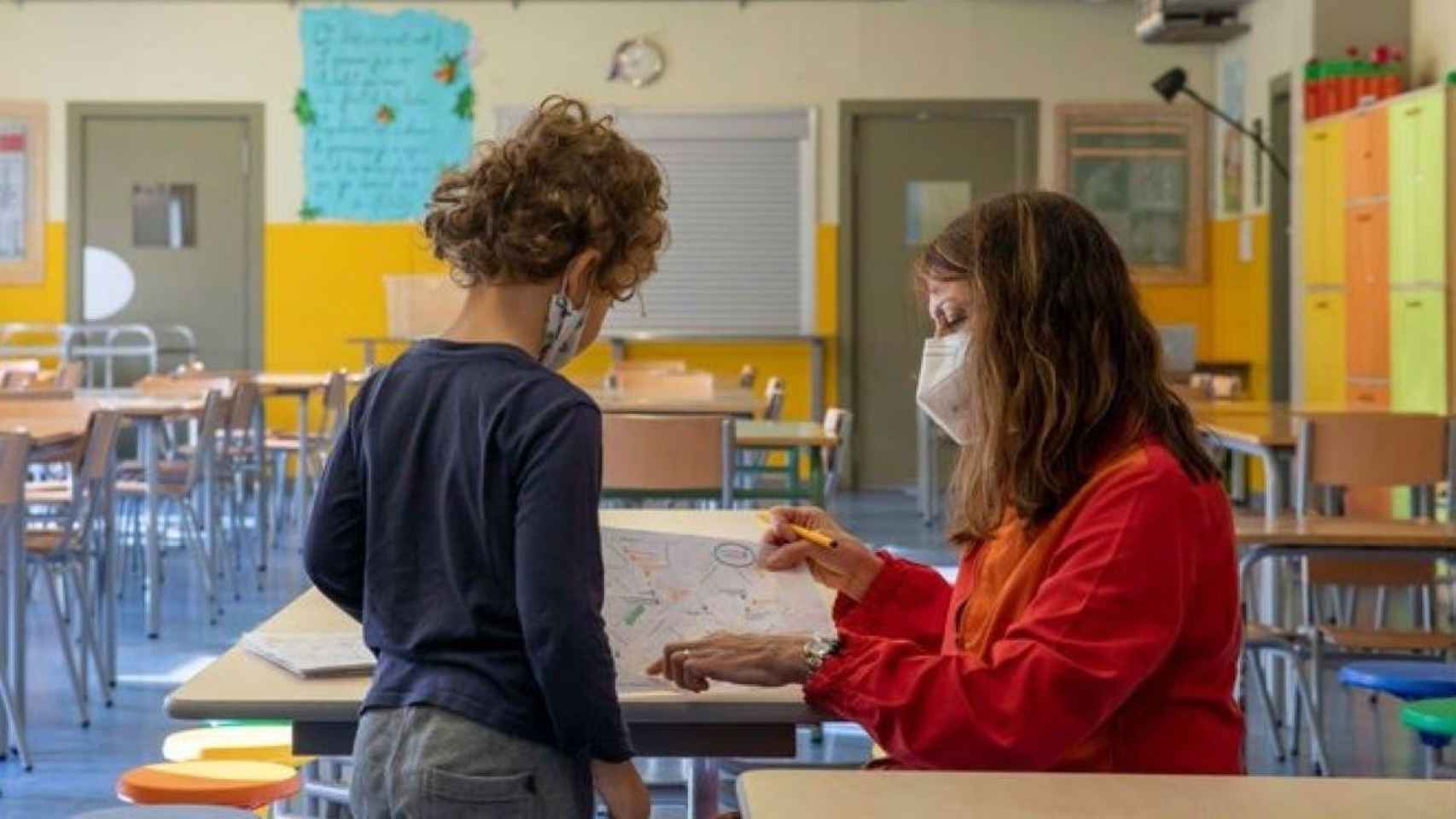 Una profesora da instrucciones a un alumno en el colegio protegida con mascarilla por el Covid / EP