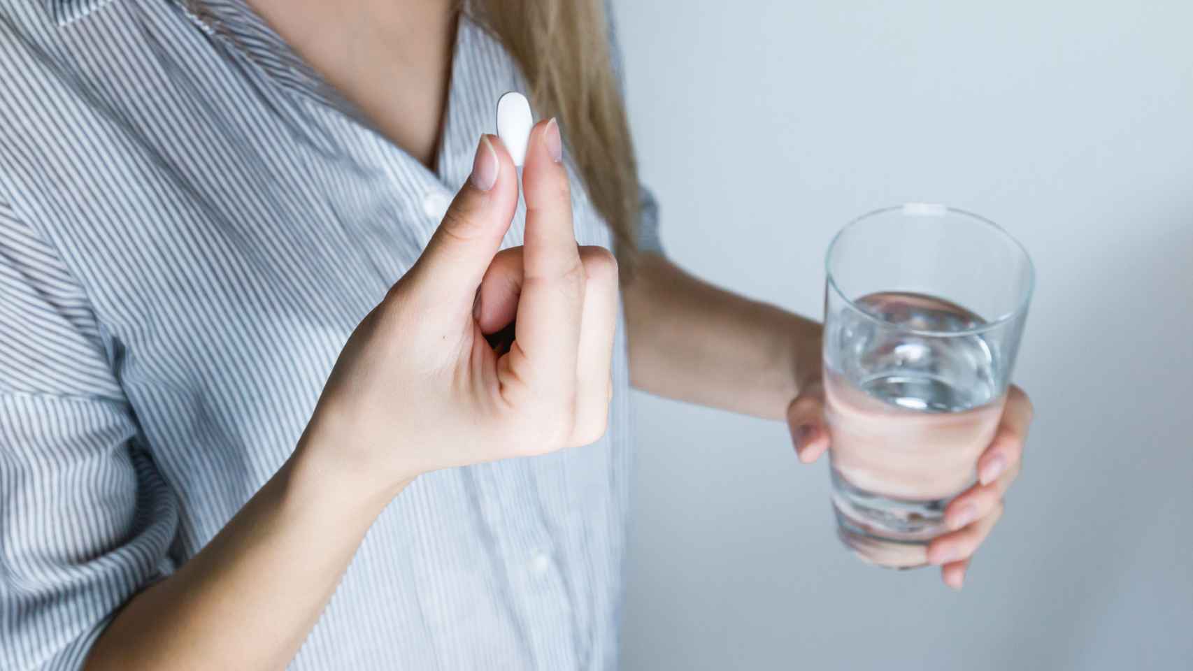 Una mujer tomandóse una píldora, como podría ser la anticonceptiva