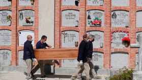 Cuatro trabajadores funerarios, enterrando un ataúd en el Cementerio de La Almudena de Madrid / EFE