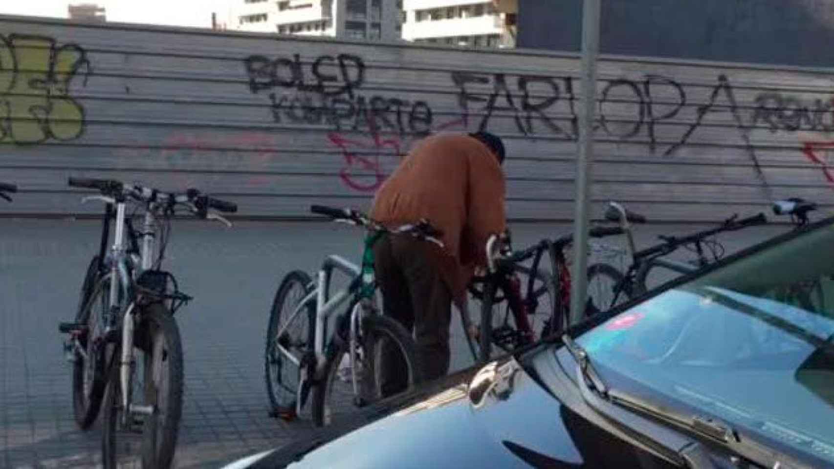 El presunto ladrón, serrando la cadena de una bicicleta en Barcelona / CG