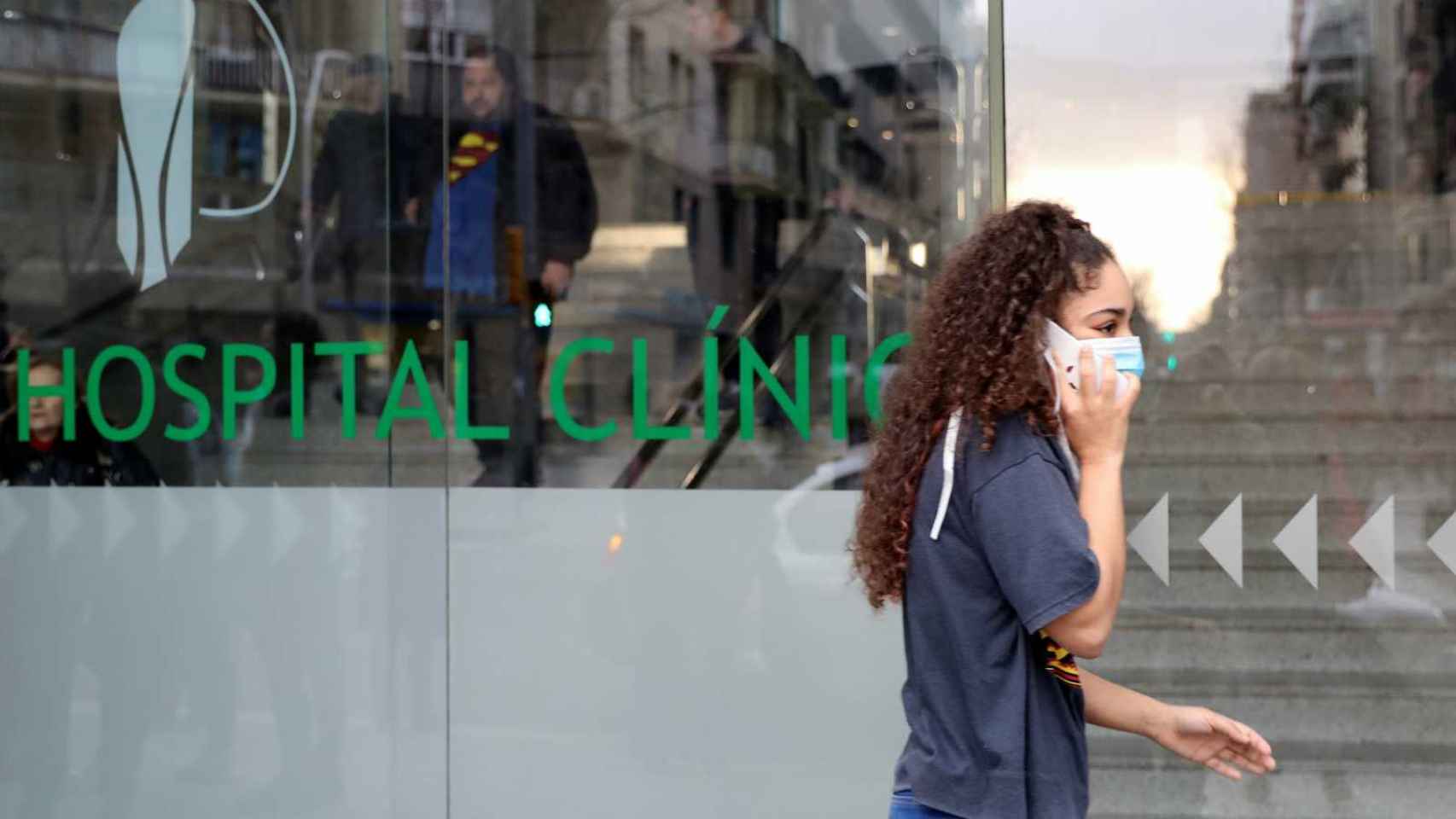Una joven pasa con mascarilla delante del Hospital Clínic durante la pandemia del coronavirus
