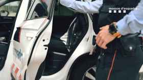 Imagen de un agente de los Mossos con un detenido sentado en el coche policial / MOSSOS D'ESQUADRA