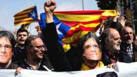 Manifestantes con caretas del expresidente de la Generalitat prófugo, Carles Puigdemont, levantando el puño y protestando contra España / EFE