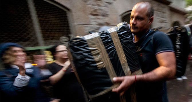Un voluntario carga una urna envuelta en plástico en un colegio electoral para el referéndum ilegal del 1-O en Cataluña / EFE