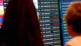 Dos personas consultan los paneles informativos del aeropuerto de El Prat, que reflejan cancelaciones de vuelos a causa del temporal / EFE