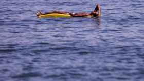 Un joven en una colchoneta en el mar en una foto de archivo / EFE