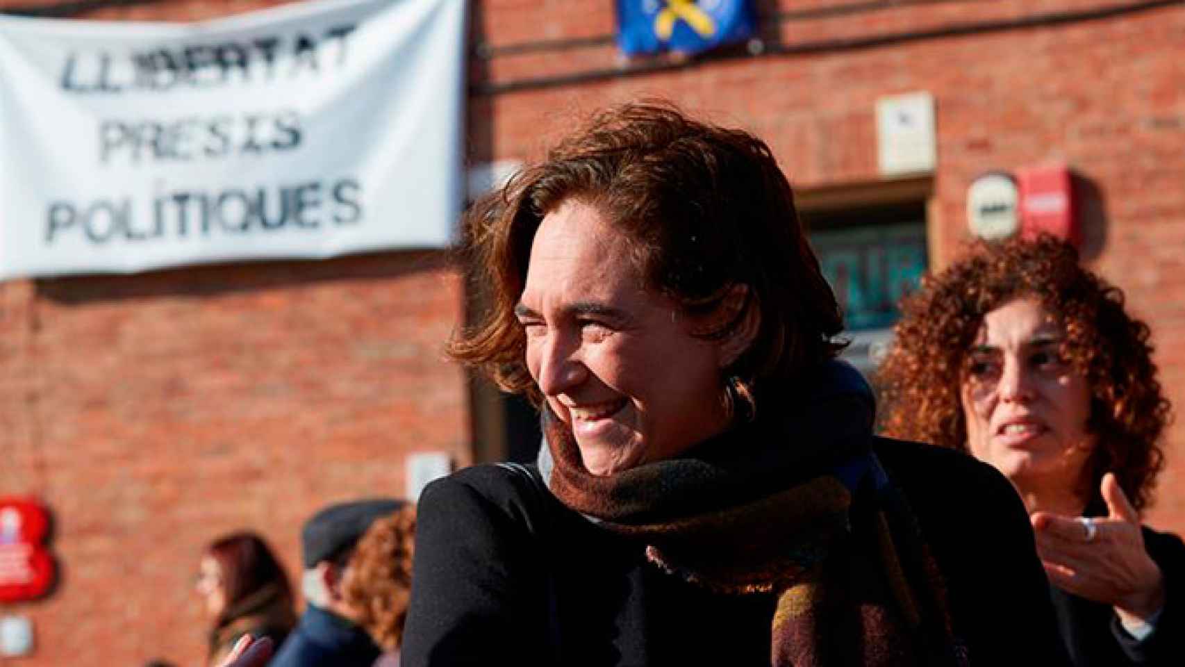 La alcaldesa de Barcelona, Ada Colau, en la fiesta y desfile de los Tres Tombs del barrio de Sant Andreu, con una pancarta de Libertar presas políticas al fondo / EFE