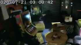 Uno de los ladrones destroza con un hacha una máquina tragaperras en un bar de Barcelona / ARTURO FERNÁNDEZ-TWITTER