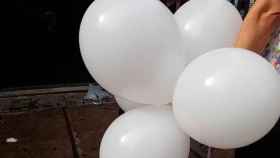 Una mujer con varios globos blancos para lanzar en el homenaje de los comerciantes a las víctimas del 17A / EP