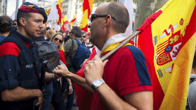 Un hombre partidario de un único gobierno central con la bandera de España saluda a un agente de Mossos en una manifestación / EFE