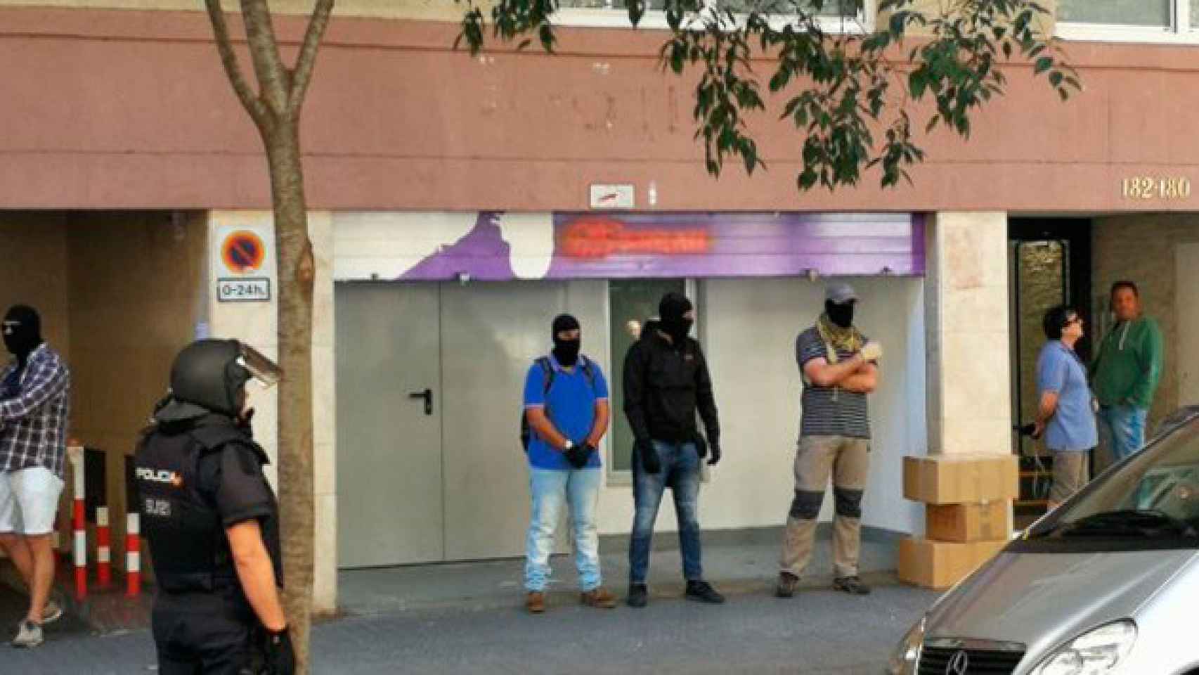 Agentes de la Policía Nacional vestidos de paisano y encapuchados en la puerta del almacén de la sede nacional de la CUP en el marco de la macrooperación de la que ha informado el TSJC / CG