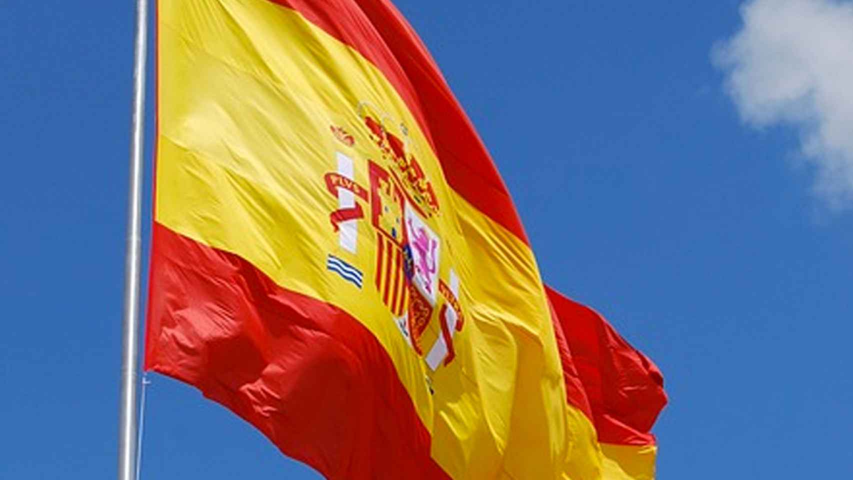 La bandera española constitucional ondea sobre un cielo azul intenso / CG
