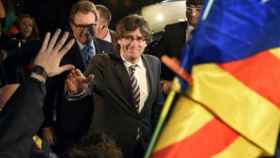 El presidente Carles Puigdemont, con Artur Mas en segundo término, saludados en un mitin con la bandera independentista / EFE