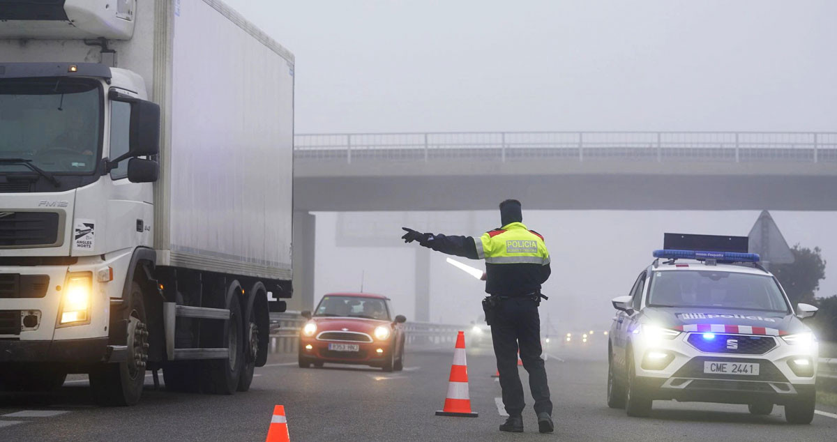 Imagen de un mosso d'esquadra dirigiendo el tráfico entre la niebla / EFE