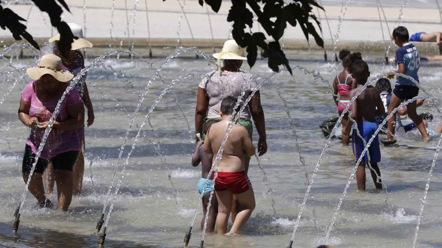 Gente se refresca en una fuente durante la ola de calor / EFE