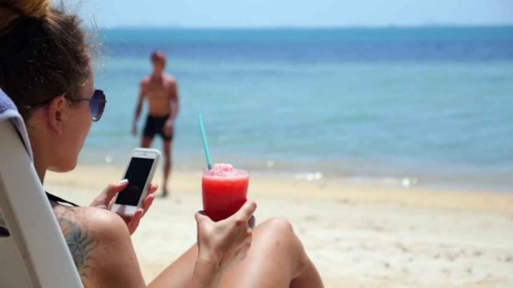 Una chica consulta su móvil en la playa durante sus vacaciones