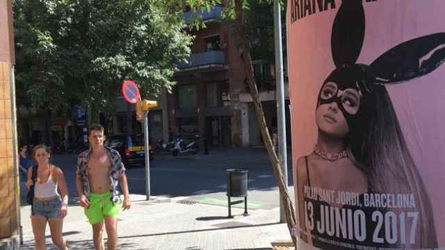 Unos turistas aprecian el cartel que anuncia el concierto de Ariana Grande en Barcelona en la calle Sardenya / CG