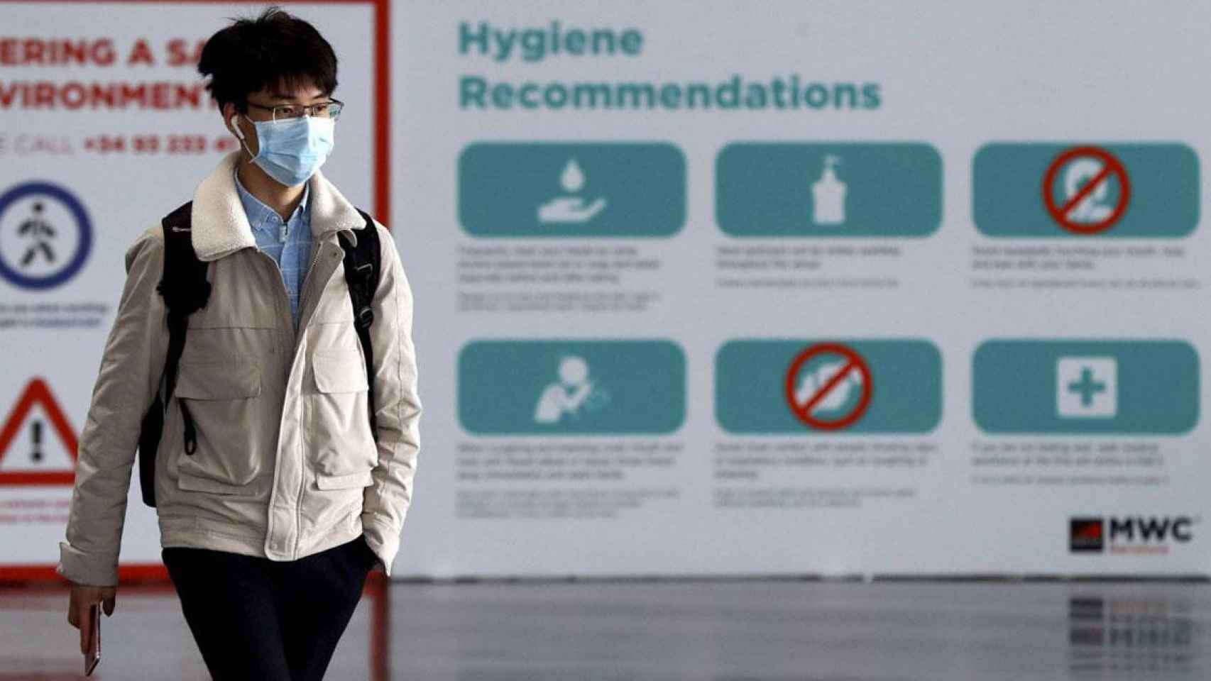 Una persona pasea ante las recomendaciones de higiene del Mobile por el coronavirus / EFE
