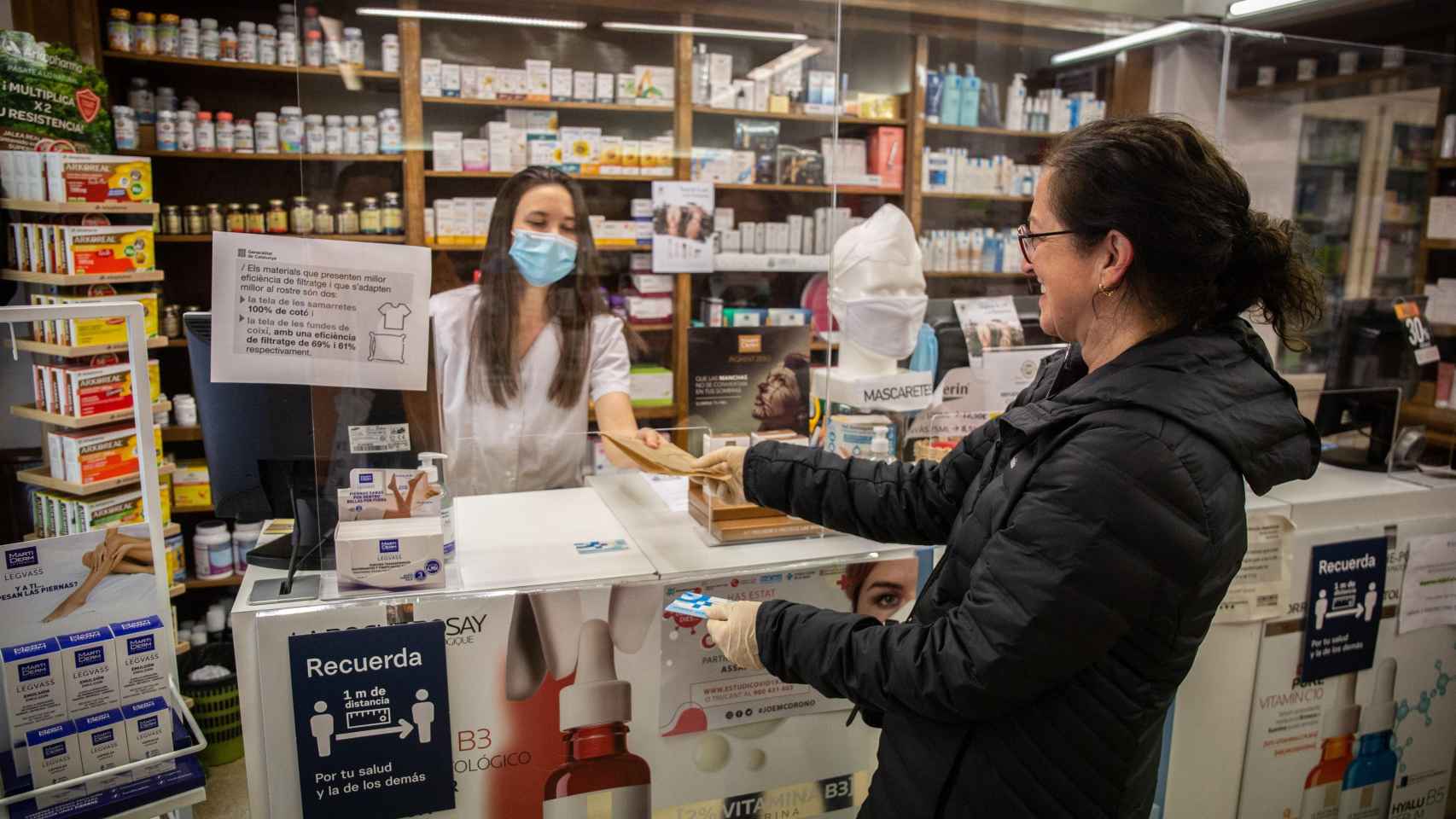 Una dependienta atiende a una clienta en una farmacia, Farmacias / EP