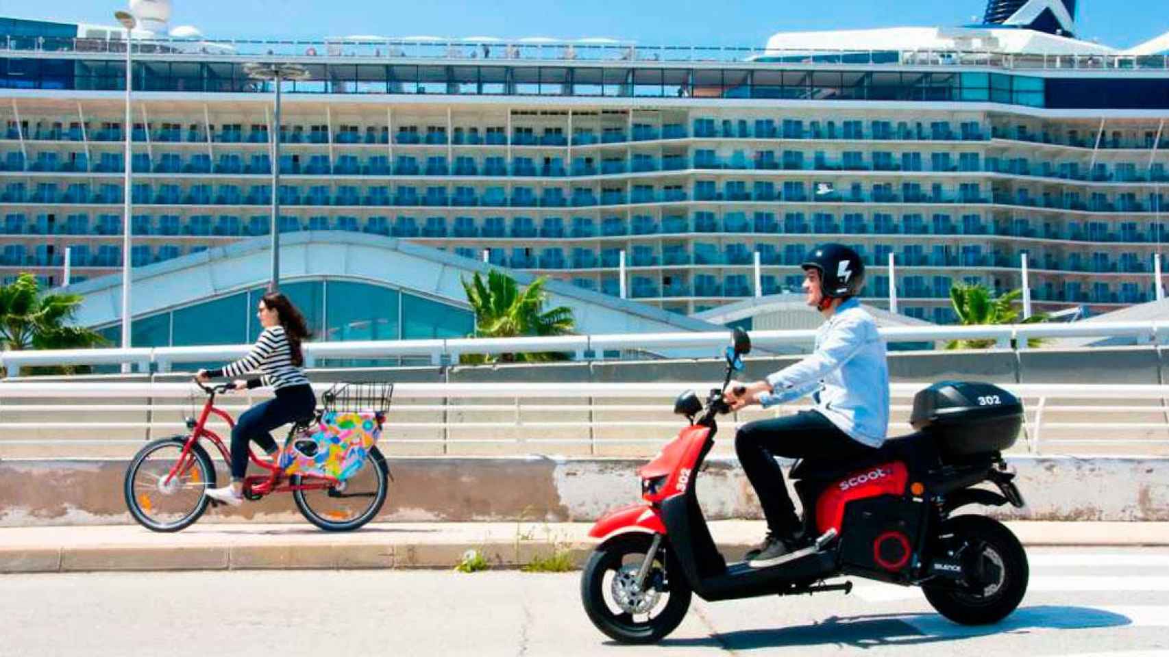 Imagen de una moto eléctrica y una bicicleta Scoot frente a un crucero en Barcelona / CG