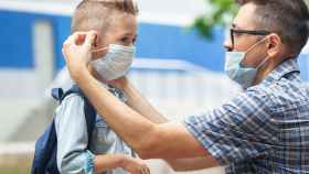 Un padre pone la mascarilla a su hijo por el protocolo contra el coronavirus en las escuelas / EP