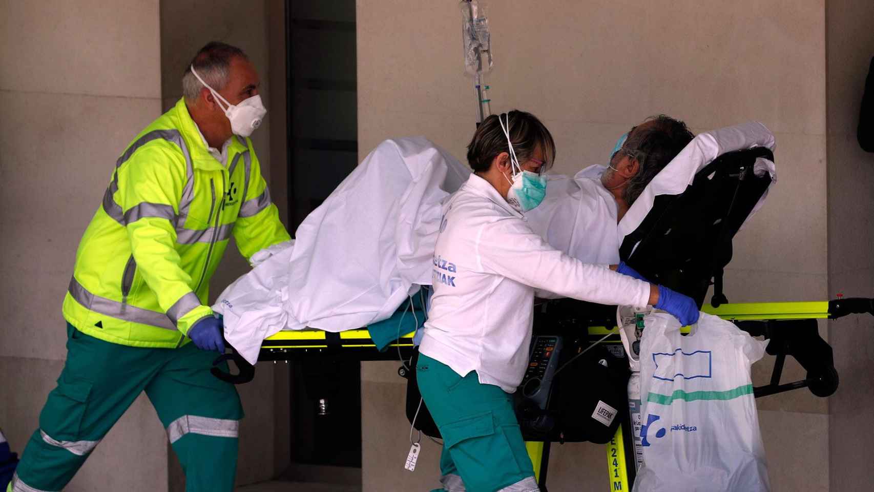 Dos médicos protegidos ante el coronavirus trasladan a un paciente / EFE