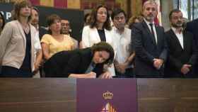 La alcaldesa de Barcelona, Ada Colau, firma el libro de condolencias en el ayuntamiento bajo la mirada de algunos concejales del consistorio barcelonés / EFE