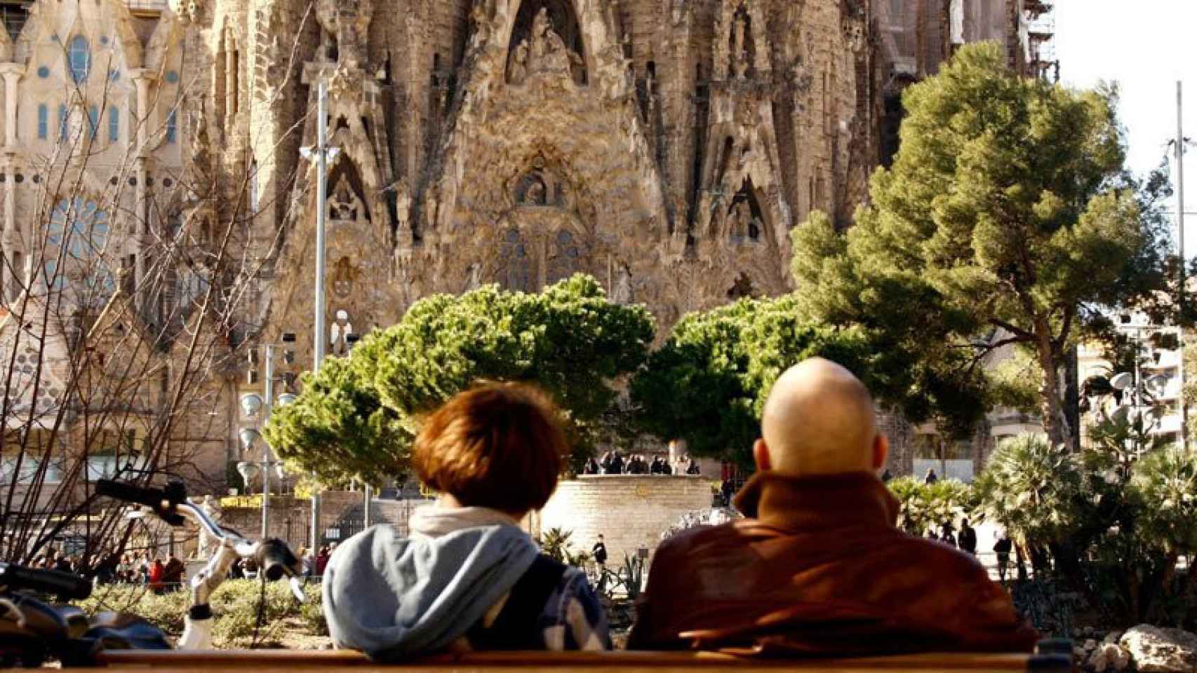 Dos turistas contemplan la Sagrada Familia de Barcelona.